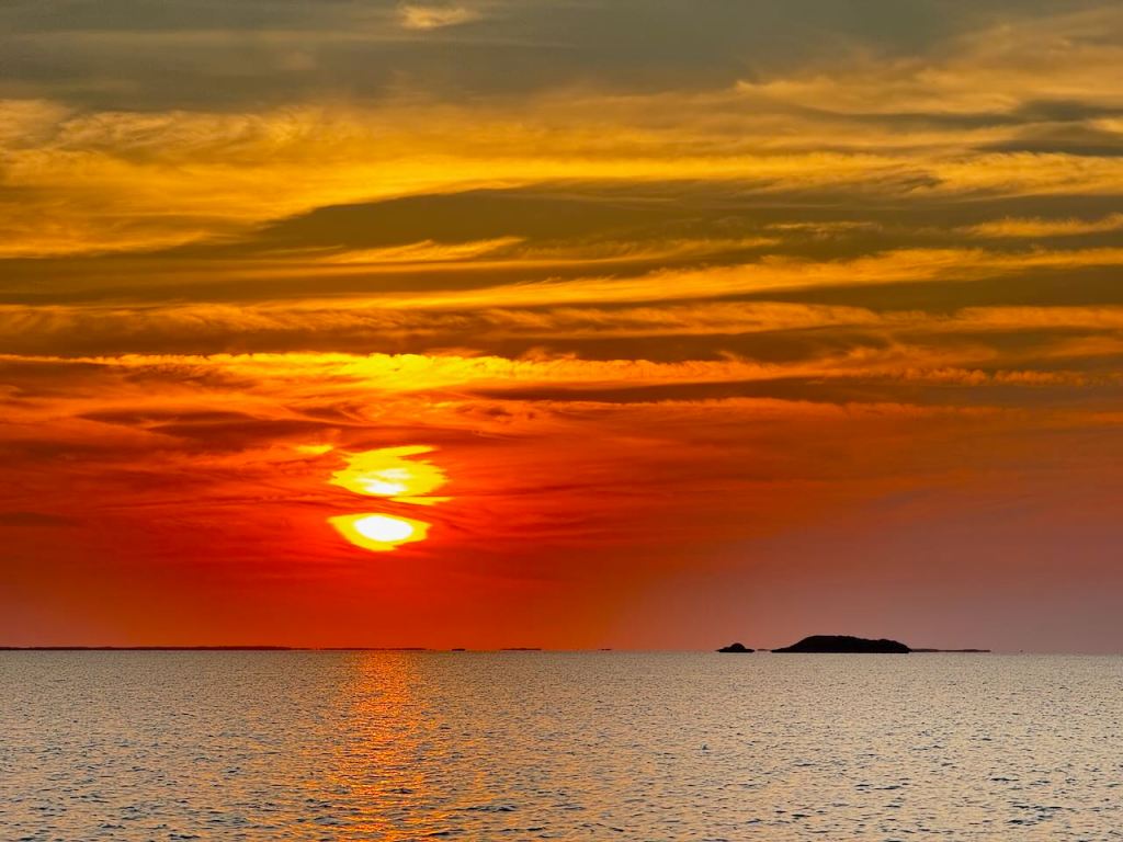 an orange and red sunset over the water while on an Exuma Bahamas boat tour